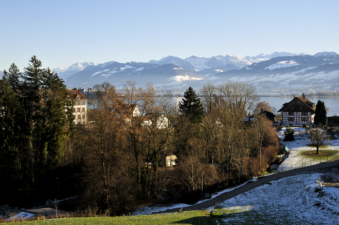 Feldbach mit Schulhaus, Schloss Rapperswil und Schwyzer Alpen vom Giessenpass gesehen